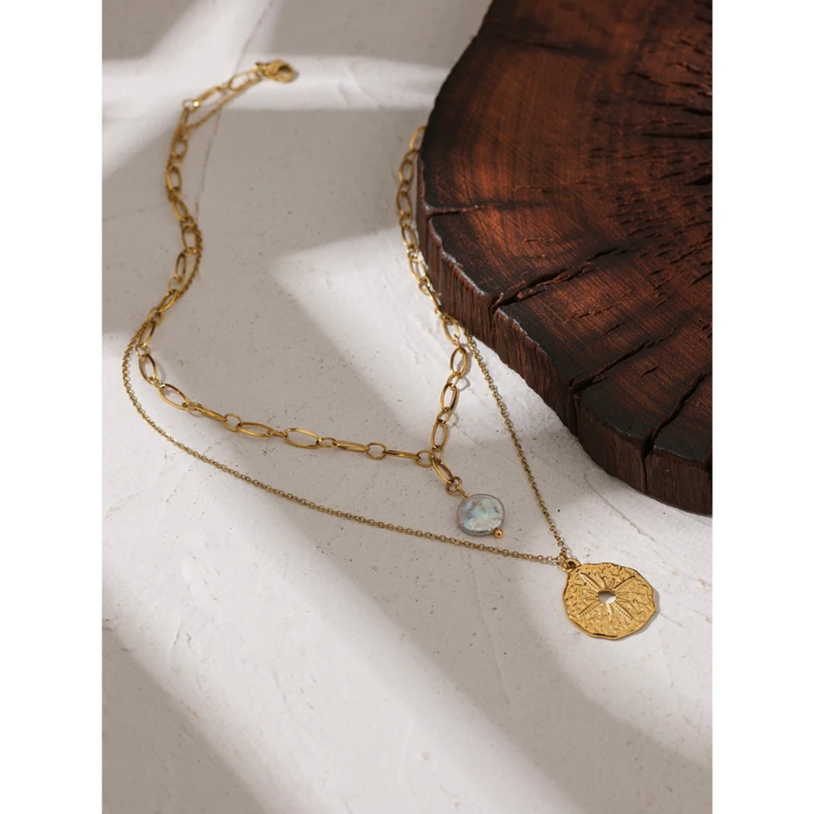 A smiling woman wearing a beautiful waterproof north star layered necklace, featuring a round pendant with a freshwater pearl charm, crafted from high-quality 18k gold plating